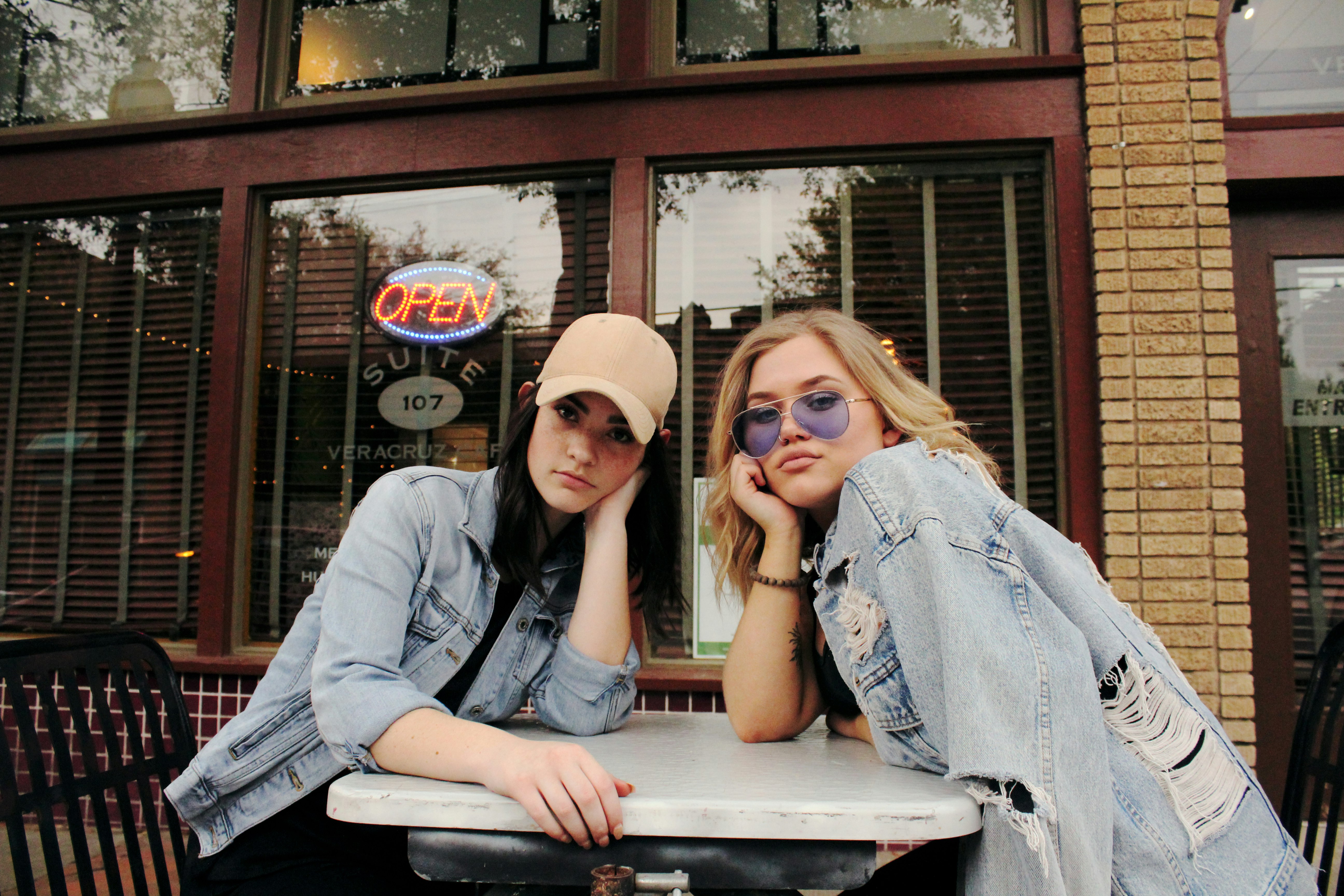 two women in gray chambray jackets sits beside table